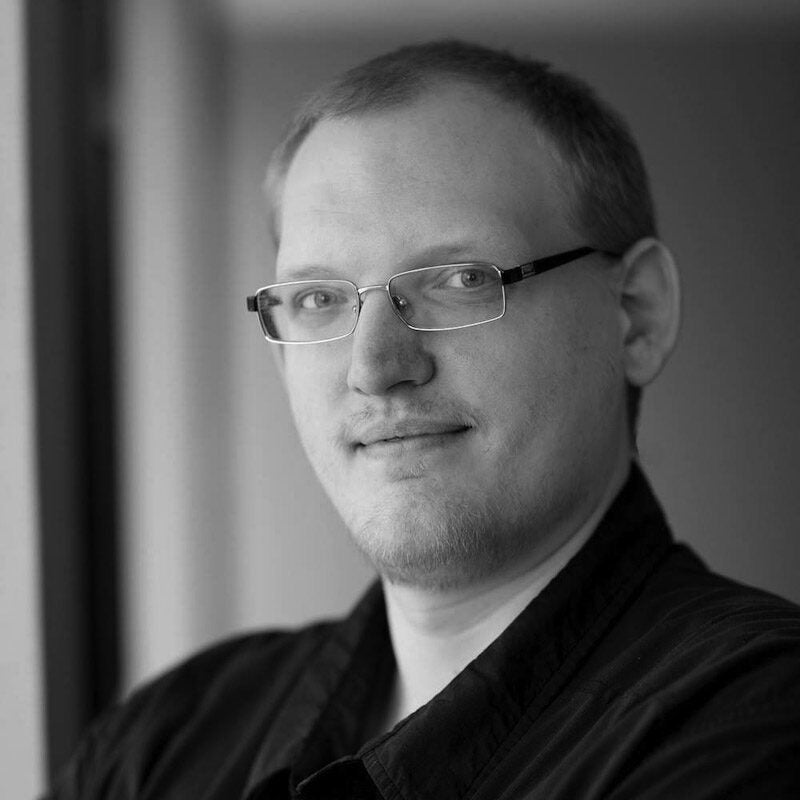 A black and white headshot of Aaron Boyd, a Senior Industrial Pentester at the industrial cybersecurity company Dragos, Inc