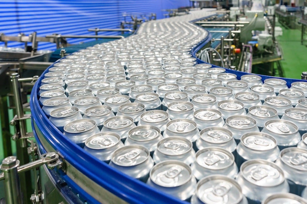 Conveyor line carrying thousands aluminum beverage cans at factory. Concept of industrial growth