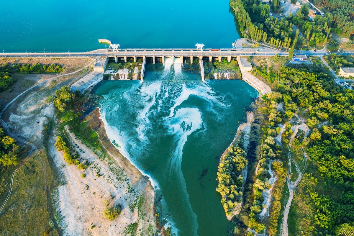 Aerial panoramic view of concrete Dam at reservoir with flowing water, hydroelectricity power station, drone shot.