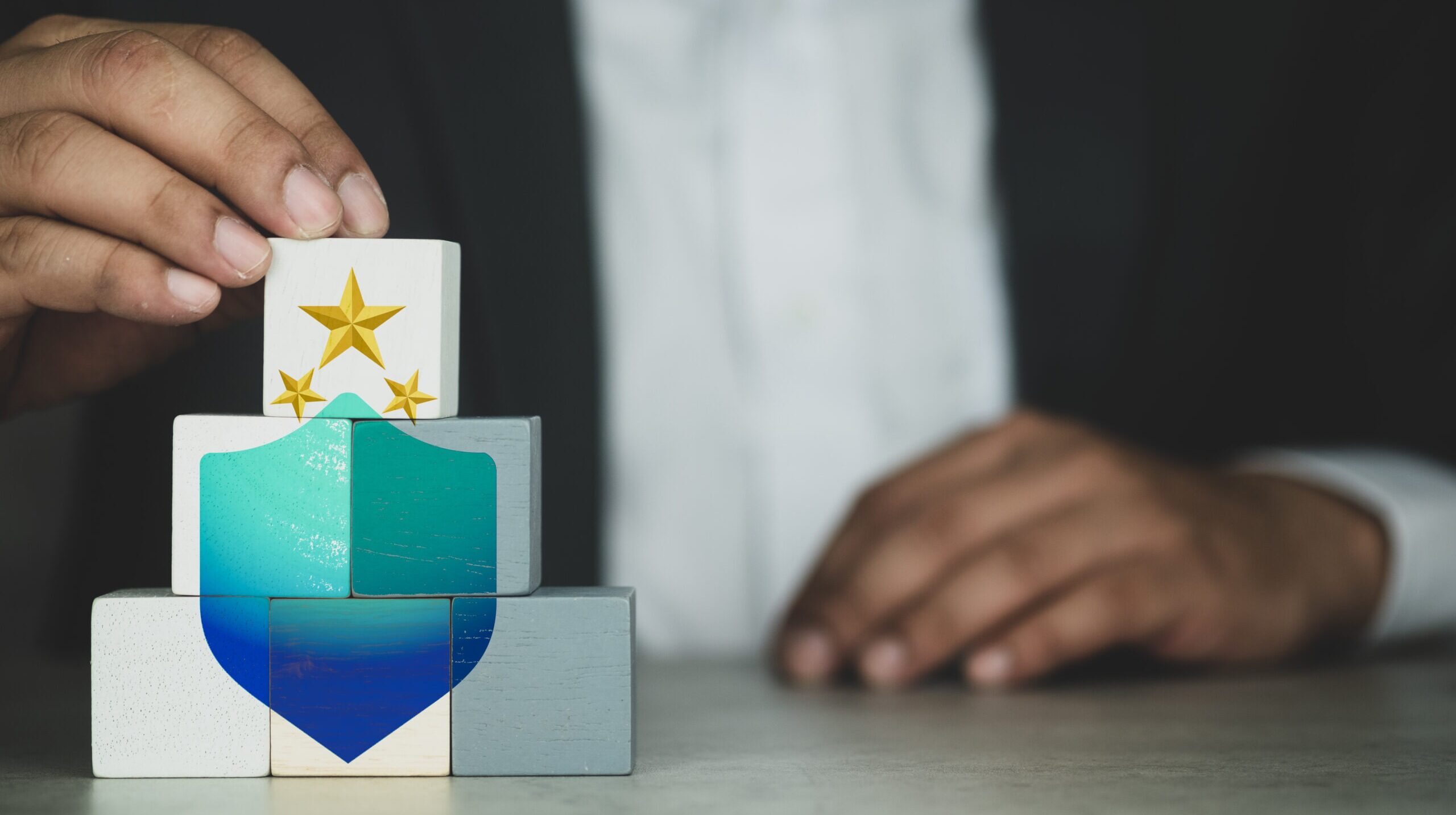 Hand touch white wood cube block on top pyramid with icon shield and stars. The concept of technology internet cyber security and anti virus online