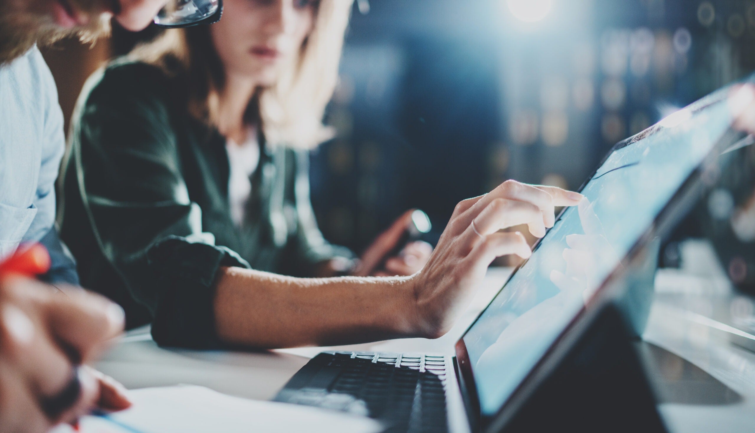 Woman pointing on digital tablet screen at night office .Horizontal.Blurred background.Flares